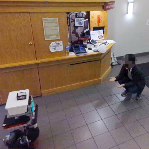 Person kneeling down to greet a mobile robot